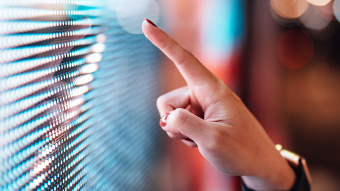 Eine Frauenhand zeigt mit dem Finger über eine digitale Oberfläche.