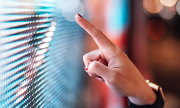 Eine Frauenhand zeigt mit dem Finger über eine digitale Oberfläche.