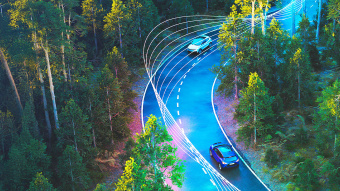 Autos von oben fotografiert fahren durch einen Wald. Zu sehen sind außerdem dynamische Fahrlinien.