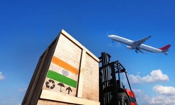 International Business und Welthandel: Ein Frachtflugzeug hebt vom Flughafen ab, im Vordergrund sieht man Container und einen Gabelstapler - Freihandelsabkommen EU/Indien
