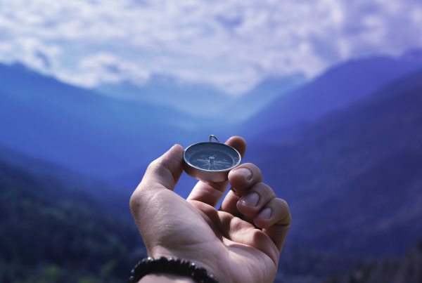 Hand hält Kompass vor Bergpanorama, Warum Finanzunternehmen eine Purpose-Story brauchen