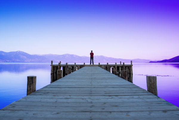 Mann steht auf Steg und blickt auf den See und die Landschaft, Symbolbild für regulatorische Neuerungen für Banken in 2024