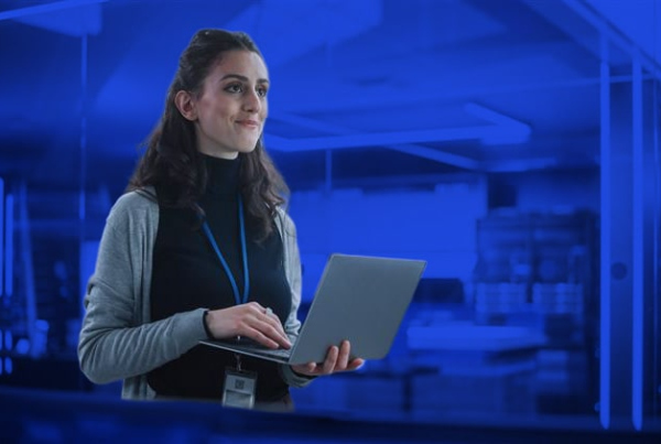 Lächelnde Frau, die einen Laptop benutzt und sich im Büro umsieht.