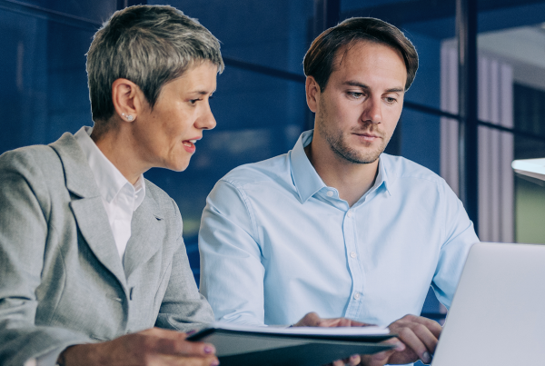 Kollegen besprechen sich vor dem Laptop, DORA-Compliance und Service Now